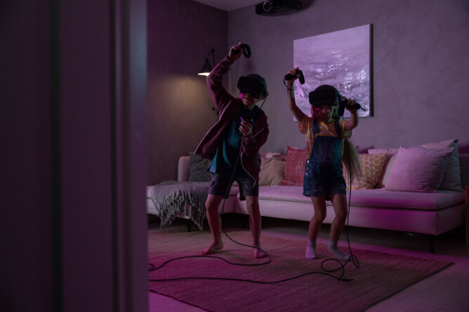 Lapset fiilistelevät peliä kuulokkeet päässään